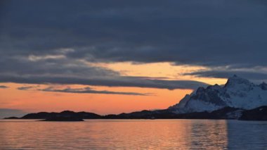 Etkileyici yolculuklar. Norveçli Fjord Sunset Cruise. Karlı dağda sinematik pembe gün batımı. Norveç kutup denizinin karla kaplı fiyortlarla çevrili manzarası. Seyahat kavramı.
