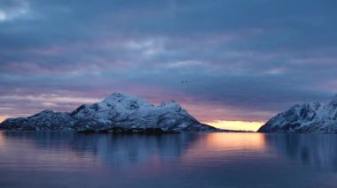 Etkileyici yolculuklar. Norveçli Fjord Sunset Cruise. Karlı dağda sinematik pembe gün batımı. Norveç kutup denizinin karla kaplı fiyortlarla çevrili manzarası. Seyahat kavramı.