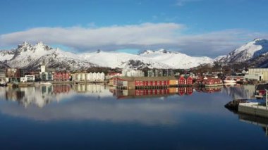 İnanılmaz bir seyahat. Deniz kıyısının uçan insansız hava aracı, karlı dağlar, kışın gün batımında daha da beter. Lofoten Adaları, Norveç. Fiyort, köy, sudaki yansıma, kayalar....