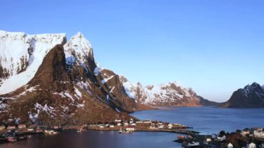 İnanılmaz bir seyahat. Deniz kıyısının uçan insansız hava aracı, karlı dağlar, kışın gün batımında daha da beter. Lofoten Adaları, Norveç. Fiyort, köy, sudaki yansıma, kayalar....