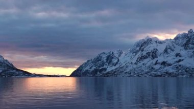Norveç fiyortlarında renkli günbatımı. Trollfjord 'a git. Lofoten Adaları 'nın karlı dağları. Etkileyici bir dağ boyunca Trollfjord 'a yelken açmak. Yat tahtasından görüntü.