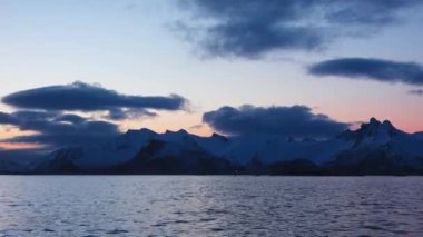 Norveç fiyortlarında renkli günbatımı. Trollfjord 'a git. Lofoten Adaları 'nın karlı dağları. Etkileyici bir dağ boyunca Trollfjord 'a yelken açmak. Yat tahtasından görüntü.