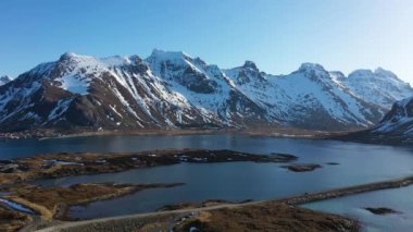 Norveç 'teki Lofoten fiyortlarının manzaraları. İHA görüntüsü. Norveç Lofoten Adası 'nın havadan görünüşü. Kar manzarası zirvesi olan Reine köyünün kış mevsimi suyu yansıtır. Norveç 'te kırmızı rorbu evleri.