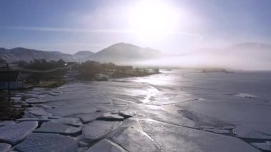 Norveç 'teki Lofoten fiyortlarının manzaraları. İHA görüntüsü. Norveç Lofoten Adası 'nın havadan görünüşü. Kar manzarası zirvesi olan Reine köyünün kış mevsimi suyu yansıtır. Norveç 'te kırmızı rorbu evleri.