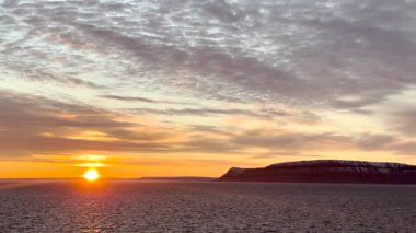 Güzel bir günbatımına tanık olun. Dağların üzerine canlı renkler döküyor ve Kuzey Kutup Dairesi 'ne yakın sakin okyanus sularına. Gökyüzü çarpıcı pembe ve turuncu renklerle dolu..