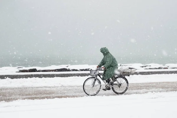 人们在海滨路上的雪地里骑自行车 — 图库照片