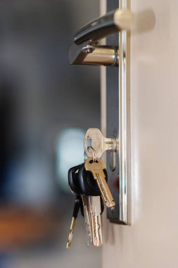 Arka planı bulanık, seçici odaklı, kapı anahtar deliğinde anahtarlık demeti