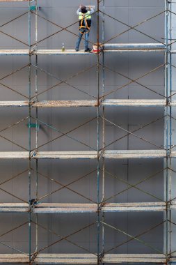 İskelede inşaat işçisi boyama için evin ön cephesini hazırlıyor.