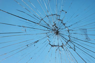 Broken glass, glass cracked from an accident on a blue sky background clipart