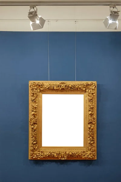 Old style vintage golden frame on the illuminated blue background. Art gallery interior