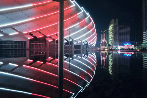 stock image Batumi, Georgia, October, 27, 2021: View of the colorful illuminated stadium and night city with modern architecture reflecting on the water surface 