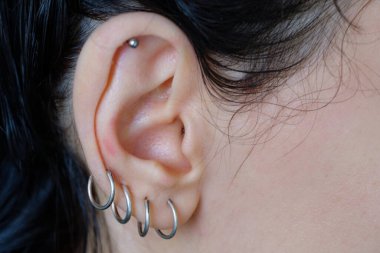 Kulağında piercing var. Farklı tip kadın küpeleri.