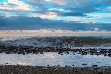 Boş çakıl taşı deniz kıyısının manzarası ve güzel bulutlu mavi gökyüzü.