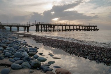 Gün batımı arka plan ile kayalık plajda iskele siluet