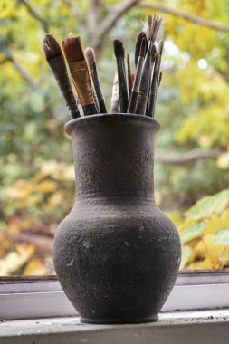 Çamur kavanozunda çeşitli profesyonel boya fırçaları, seçici odak 