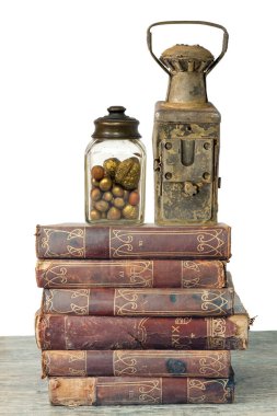 Fındık ve eski paslı lambalarla dolu eski bir kavanoz, beyaz arka planda izole edilmiş eski kitaplar.