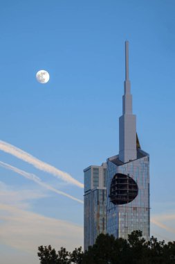 View of a full moon rising over skyscraper clipart