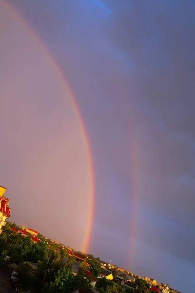 Double rainbow in dark sky after rain.