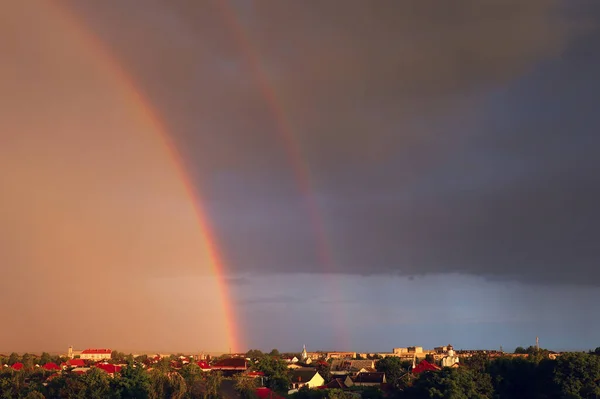Double rainbow in dark sky after rain.