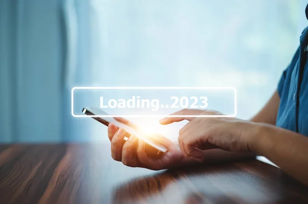 Hand using smartphone search on bar for loading 2023, start new year 2023 concept