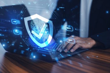 Gelişmiş siber güvenlik kalkanına sahip bir dizüstü bilgisayarda çalışan ve hassas verilerin korunmasını sağlayan ve potansiyel tehditlere karşı dijital çevreyi koruyan bir adam..