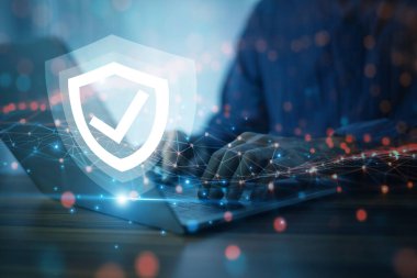 Gelişmiş siber güvenlik kalkanına sahip bir dizüstü bilgisayar üzerinde çalışan iş adamı hassas verilerin korunmasını ve potansiyel tehditlere karşı dijital ortamı güvence altına alıyor..