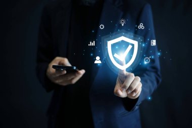 Modern iş dünyasında veri gizliliği, çevrimiçi güvenlik ve dijital dönüşümü temsil eden bir siber güvenlik kalkan hologramı tutan bir iş adamı.