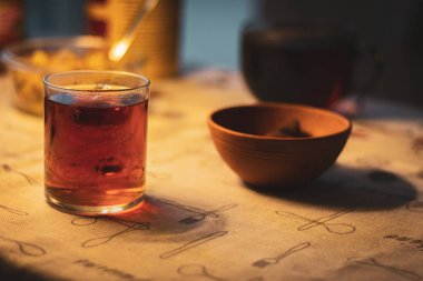 Masada bir fincan çay ve bir kutu şeker. İyi akşamlar çay saati. Çay ile sıcak bir akşam. Sıcak kış içecekleri. Ev hayattır. Çay fincanı masa örtüsünün üstünde.. 