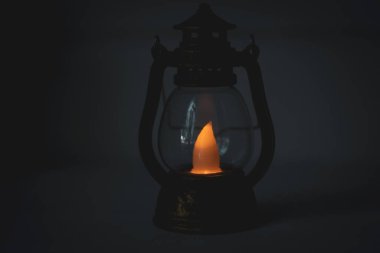 Geceleyin eski bir gaz lambası. Siyah arka planda klasik fener. Akşamları dekoratif lamba. Ukrayna 'da elektrik kesintisi. İç mekan. Karanlıkta parlayan mum ışığı. Küçük bir gaz lambası. Yıllanmış fener.