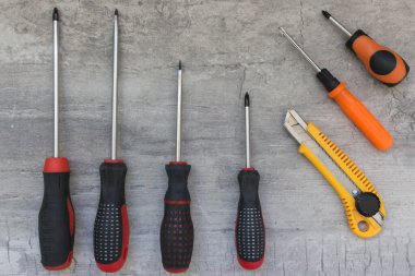 Aletler (tornavidalar ve kesme bıçağı) gri arkaplanda. Alet takımını tamir et. Alet takımı. Tornavidaların farklı boyutları.