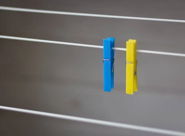Clothing peg on washing line. Clothing pins on clothesline. Clothes pin in ukrainian colors. Blue and yellow pegs. Laundry concept. Household equipment. Ukrainian national colors.