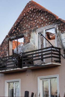 Rus istilasından sonra Ukrayna 'da yıkılmış bir bina. Evin ön cephesi mahvoldu. Ukrayna 'da savaş. Füze saldırısından sonra kırık camlar ve tuğla duvarlar. Terk edilmiş hasarlı ev. Savaş felaketi. Bombalama sonrası yıkılmış çatı ve duvarlar. 