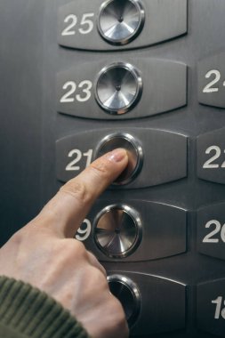Parmağını kaldır düğmesine bas. Asansör düğmesine basan kadın. Asansörde seviye seçimi. Kat numaraları paneli. Modern asansör içi. Panel kontrolü kaldırılıyor. 