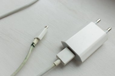 Beyaz arka planda elektrik prizi. Şarj aletinin güç kablosu kopmuş. Kablosu kopmuş. Akıllı telefon cihazı. Cep telefonu kablosu. Elektrik teli tehlikeli durumda..