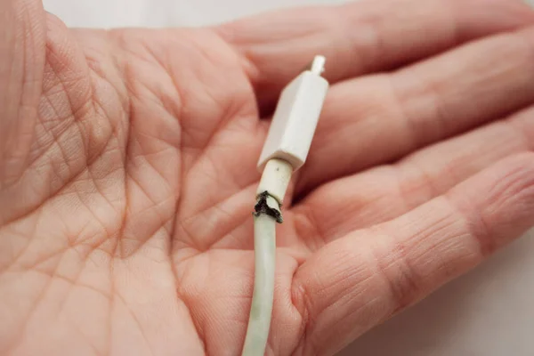 stock image Broken electric plug in hand. Broken power cord in woman hand. Broken usb cord. Smartphone device. Cable for mobile phone. Electrical wire in dangerous condition.