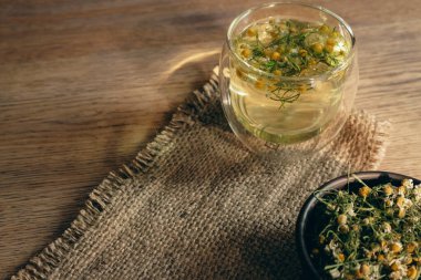 Papatya çayı ve kuru papatya çiçekleri kavanozda. Güneş ışığında papatya çayı. Eko ürünler. Doğal çay ve bitkiler. Sağlıklı beslenme. Gölge oyununda bitkisel içecek. Alternatif terapi.