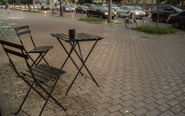 ストリートカフェテーブルと椅子 雨の日のサイドウォークカフェ 小規模な地元ビジネス 秋に空いたカフェ 外食のための公共スペース アウトドア家具 車で道路沿いのカフェ — ストック写真