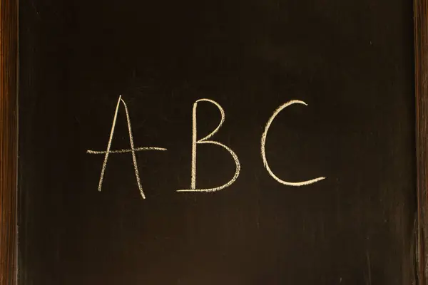 Chalk drawing on a blackboard. Letters ABC on wooden board. School chalkboard. Alphabet concept. Handwritten text. Preschool education. Knowledge concept. Language symbols with copy space.