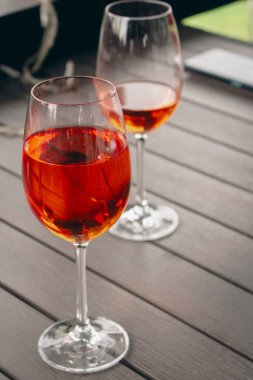 İki bardak Aperol Spritz kokteyli. Şarap kadehleri ve gül şarabı. Açık hava barı. Kaldırımdaki kafe masası. Alkol partisi. Turuncu kokteyller. Aperatif arka plan. Alkolik içecekler. Masada uzun içkiler. 