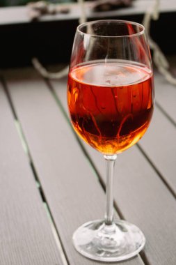 Bir bardak Aperol Spritz kokteyli. Şarap kadehi ve gül şarabı. Açık hava barı. Kaldırımdaki kafe masası. Alkol partisi. Turuncu renkli kokteyller. Aperatif arka plan. Alkolik içecekler. Masada uzun içkiler. 