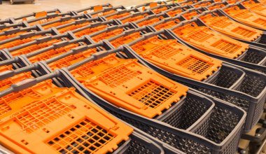 Alışveriş merkezinde alışveriş arabaları. Pazar yeri. Yığınlanmış alışveriş arabaları. Perakende yeri. Turuncu saplı alışveriş arabaları. Hipermarket içi. Alışveriş sepeti dükkanda..