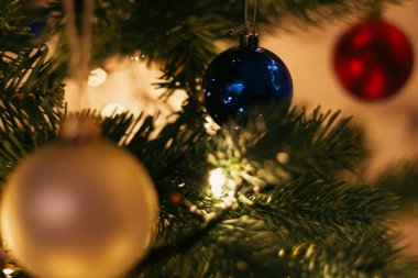 Noel ağacı süslemesi. Renkli topları ve çiçekli bir Noel ağacı. Yeni yıl partisi geçmişi. Kış tatili dekorasyonu. Mutlu Noel kutlamaları. Noel ağacında parlak mavi bir küre. 
