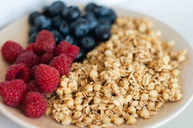 Yabanmersinli ve ahududulu müsli, yaklaşın. Yabanmersinli granola. Sağlıklı beslenme. Bir kase yulaf gevreği, yabanmersini ve ahududu. Vitamin kahvaltısı. Ev yapımı yemek. Spor yemeği. Mısır gevreği ve böğürtlen.. 