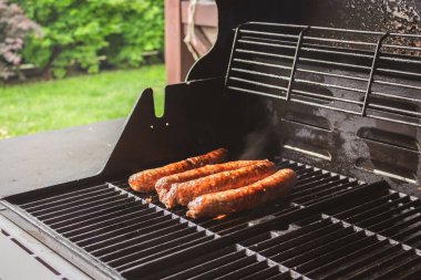 Izgarada sosisler. Bahçe barbekü partisi. Izgarada domuz sosisi var. Izgara sucuklu sucuk sosisi. Arka bahçede piknik. Sosisli sandviç. Sağlıksız yiyecekler. BBQ gıda konsepti. 