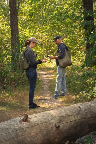 Couple lost in forest. Man and woman with mobile guide in woods. Wanderlust in autumn forest. Looking for direction. Orientation in nature. Romantic travel. Active lifestyle. Tourists with backpack on the trail.