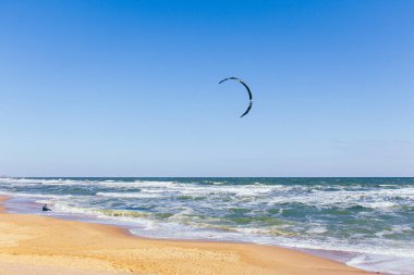 Sahilde uçurtma sörfü. Aktif yaşam tarzı. Ekstrem spor konsepti. Deniz kıyısında dalgıç kıyafetli ve uçurtma sörflü bir adam. Yaz zamanı aktif spor. Adrenalin ve özgürlük. Hava deniz manzaralı sörfçü.