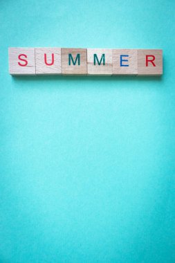 Yazın, Azul arka planındaki tahta parçalardan oluşan bir söz. Yaz tatili kavramı. Yaz yaşam tarzı. Mavi arkaplanda kopyalama alanı olan metin. Yaratıcı kartpostal. 