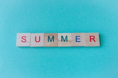 Yazın, Azul arka planındaki tahta parçalardan oluşan bir söz. Yaz tatili kavramı. Yaz yaşam tarzı. Mavi arkaplanda kopyalama alanı olan metin. Yaratıcı kartpostal. 