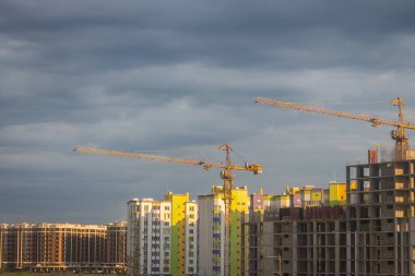 Akşamları vinçleri olan bir inşaat alanı. Gün batımında Kyiv dönüm noktası. Yeni binalar inşa ediliyor. Ukrayna 'nın başkenti Kyiv' de. İnşaat endüstrisi. Şehir mimarisi.