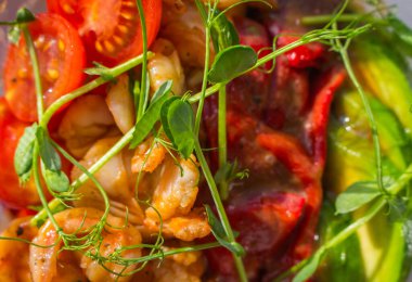 Grilled shrimps, red bell pepper with avocado and tomato in plastic bowl. Poke bowl in sunlight. Traditional asian food. Street food to go. Healthy eating concept. Seafood poke bowl with bean sprouts.
